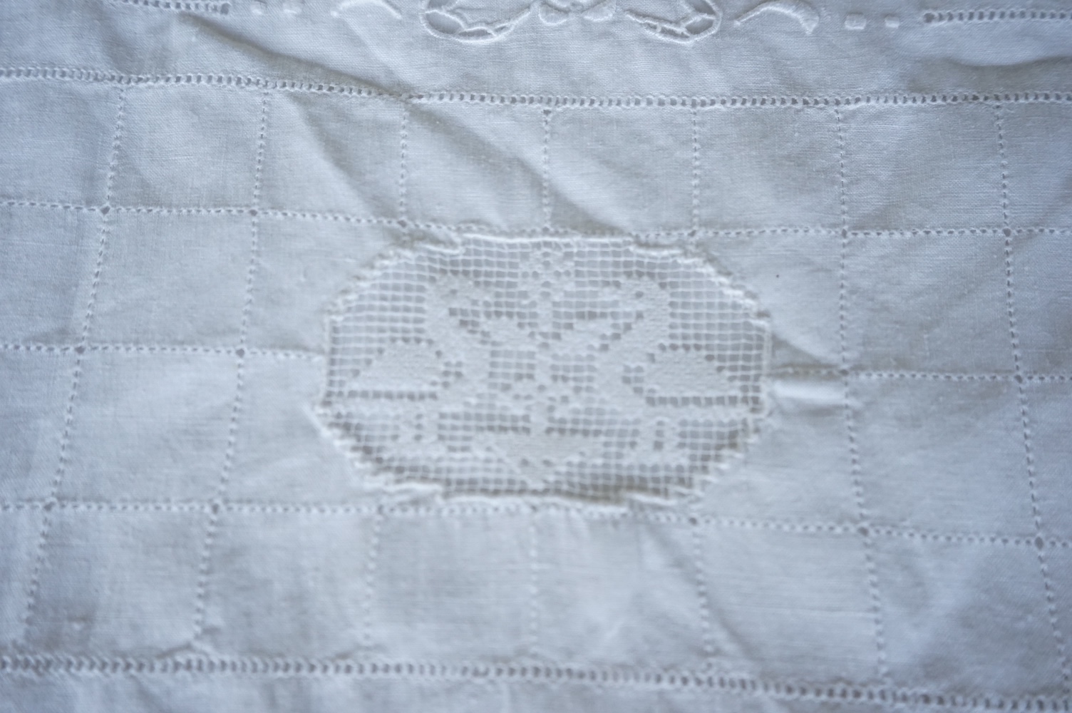 A late 19th century early 20th century finely woven, hand worked linen sheet 6’8”wide, together with a near matching large square pillowcase. Both items worked in Embroidery Anglaise, button holed and inset and trimmed w
